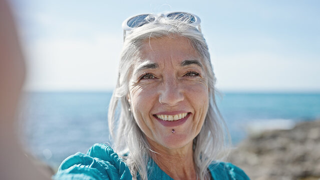 Middle age grey-haired woman tourist making selfie by the camera at beach