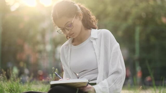 Sad indian woman student or freelancer with lack of new ideas or creative block writing and crossed out at green park Worried female working or studying outdoors