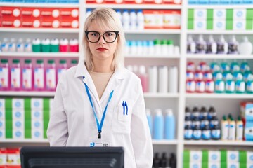 Young caucasian woman working at pharmacy drugstore skeptic and nervous, frowning upset because of...