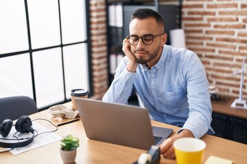 Young hispanic man business worker tired using laptop working at office