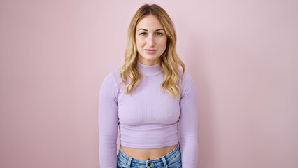 Young beautiful hispanic woman standing with serious expression over isolated pink background