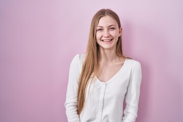 Fototapeta premium Young caucasian woman standing over pink background winking looking at the camera with sexy expression, cheerful and happy face.