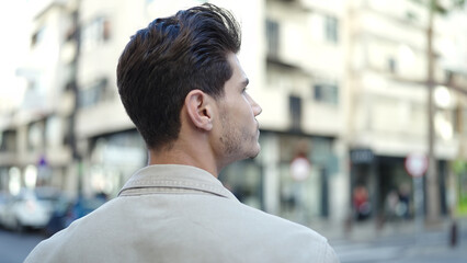 Young hispanic man standing on back view at street