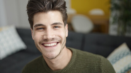 Obraz premium Young hispanic man smiling confident sitting on sofa at home