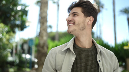 Young hispanic man smiling confident looking to the side at park