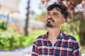 Young hispanic man looking to the sky with relaxed expression at park