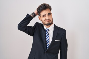 Young hispanic man with tattoos wearing business suit and tie confuse and wondering about question....
