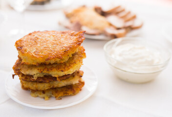 Fried grated potato pancakes with sour cream on white plate