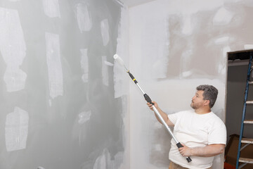 Apartment room was updated, improved during repairs, using roller to paint walls with white paint