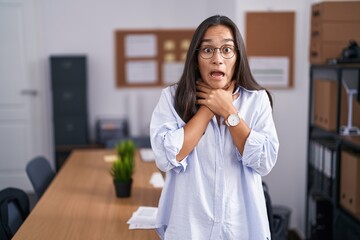 Young hispanic woman at the office shouting suffocate because painful strangle. health problem. asphyxiate and suicide concept.