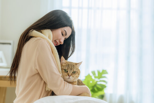 Young Asian Woman Holding Cat Tightly in Bedroom Morning