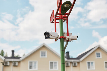 Videcam on a pole. Security system. Video surveillance of the street and houses.