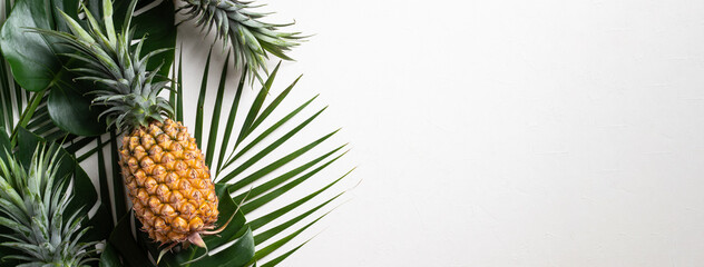 Fresh pineapple with tropical leaves on white background.