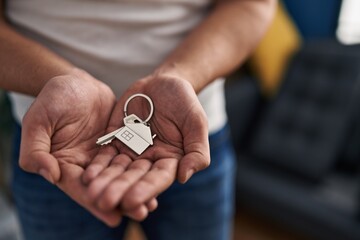Young hispanic man holding key at new home