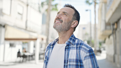 Middle age man smiling confident looking to the sky at street
