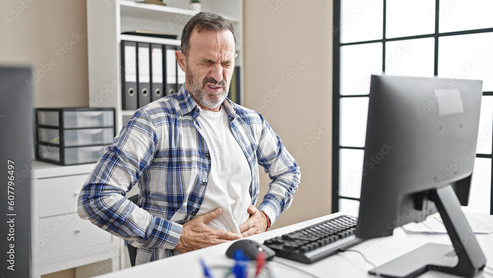 Wall mural Middle age man business worker suffering for stomachache working at office