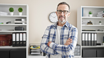 Middle age man business worker standing with arms crossed gesture and serious expression at office