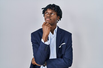 Young african man with dreadlocks wearing business jacket over white background with hand on chin thinking about question, pensive expression. smiling with thoughtful face. doubt concept. - Powered by Adobe