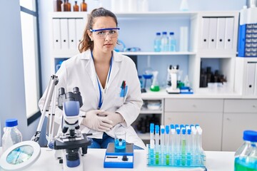 Fototapeta premium Young hispanic woman working at scientist laboratory with hand on stomach because nausea, painful disease feeling unwell. ache concept.