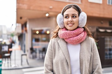 Young beautiful hispanic woman smiling confident wearing scarf and earmuff at street