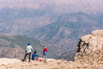 Tourists and hikers enjoying the view of highlands of Iran in the mid day sun, peaks, no vegetation, mountain chain, Alborz mountain range  