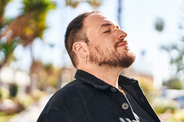 Young hispanic man smiling confident breathing at park