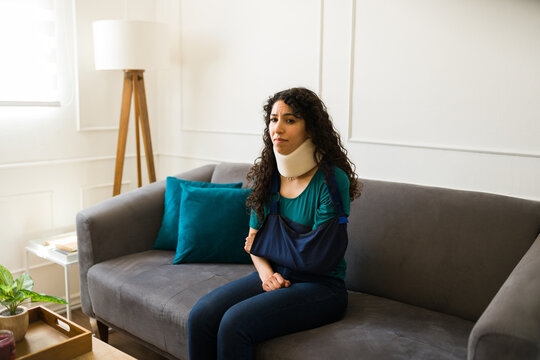 Injured woman with a broken arm using a neck brace at home