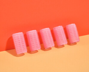 Pink hair curlers for voluminous and beautiful styling stand in row. Idea of beauty.