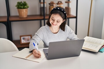 Young woman with down syndrome sitting on table studying at home