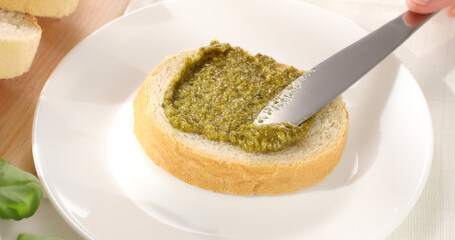 man spreads pesto on bread with a knife. close-up. angle view. making a sandwich. italian sauce....