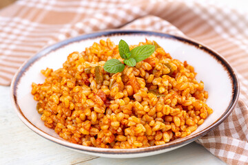 Traditional turkish bulgur pilaf with tomato sause in plate (Turkish name; meyhane pilavi)