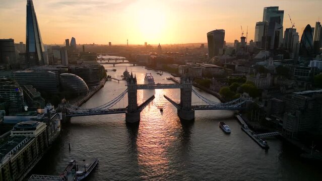Beautiful aerial sunset view of the lifted open Tower Bridge and skyline of London with orange sunlight and ship traffic on the river Thames