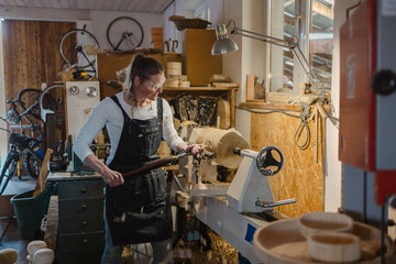 Craftswoman carving wood in a carpentry workshop 
