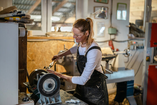 Craftswoman carving wood in a carpentry workshop 
