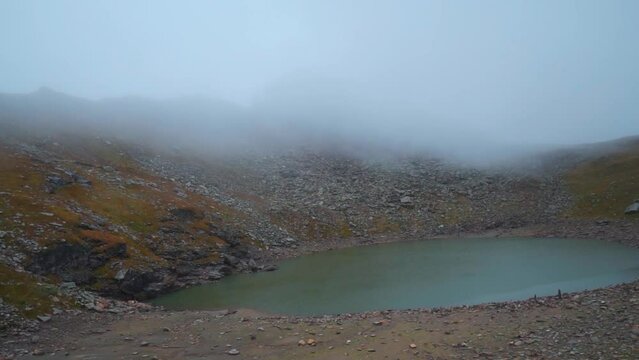 Holy Brigu Lake in Manali high on the mountains of Himalayas at Himachal Pradesh, India. Bhrigu lake covered with clouds in summer season. Mountain lake and clouds. Trekking in Himalayas.