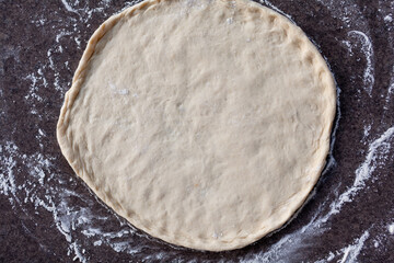 Rolled out pizza dough on floured slate surface, photographed overhead with natural light - Powered by Adobe