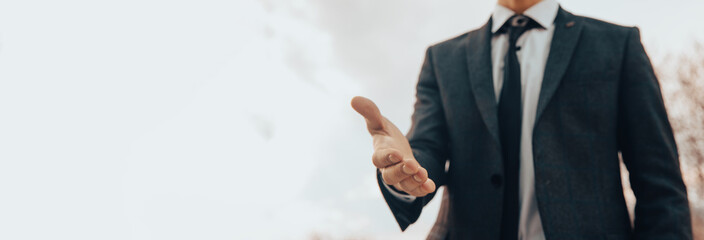 A man in a suit holds out his hand for a handshake
