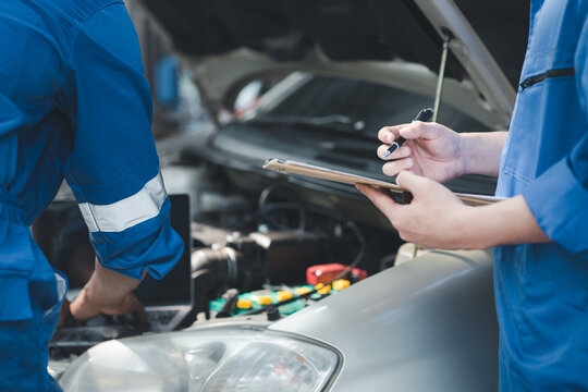 Two professional car mechanics are helping to inspect a customer's car being brought in for repair, all types of auto specialists, expert car repairs and certified auto repair centers.