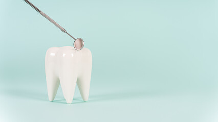 Dental clinic special offer. Healthy white tooth model and dentist mirror on a blue background. Copy space. Teeth care and whitening, dental treatment, tooth extraction, implant concept.