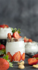 Greek yogurt, nuts and strawberries in a glass jars on grey table close up, copy space