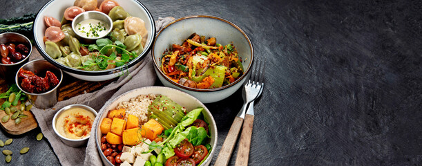 Vegetarian and various vegan dishes on dark table.