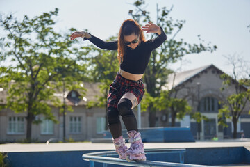 Cool young roller blader female grinding on a rail in a skatepark. White female person wearing...