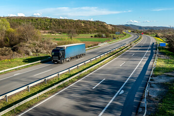 
Highway transportation scene with blue transportation truck on a rural highway under a beautiful blue sky