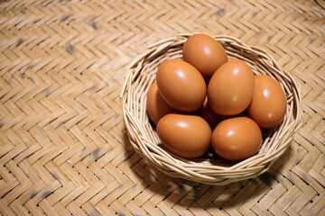 Close-up view of raw chicken eggs in egg basket on brown wooden background