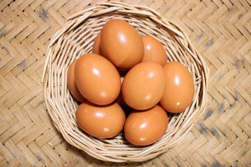 Close-up view of raw chicken eggs in egg basket on brown wooden background