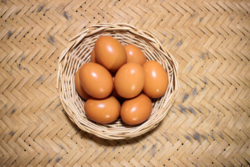 Close-up view of raw chicken eggs in egg basket on brown wooden background