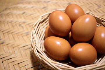 Close-up view of raw chicken eggs in egg basket on brown wooden background