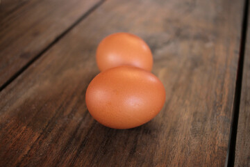 Close-up view of raw chicken eggs in egg basket on brown wooden background
