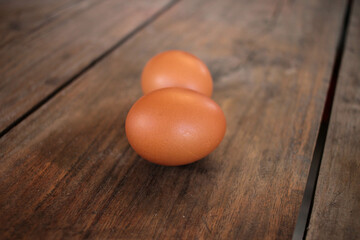 Close-up view of raw chicken eggs in egg basket on brown wooden background