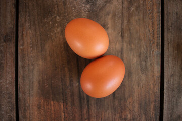 Close-up view of raw chicken eggs in egg basket on brown wooden background